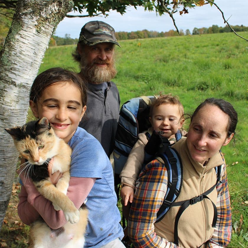 Four members of the Clark, Webb Clark family pose and a girl holds a cat on their Maine farm.