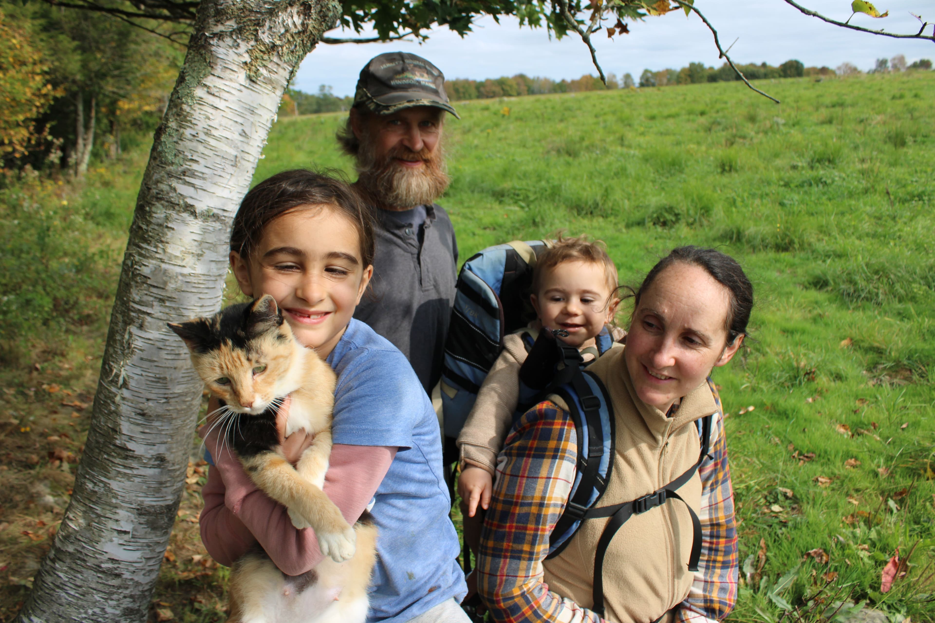 An Organic Valley farm family standing by a tree in their pasture.